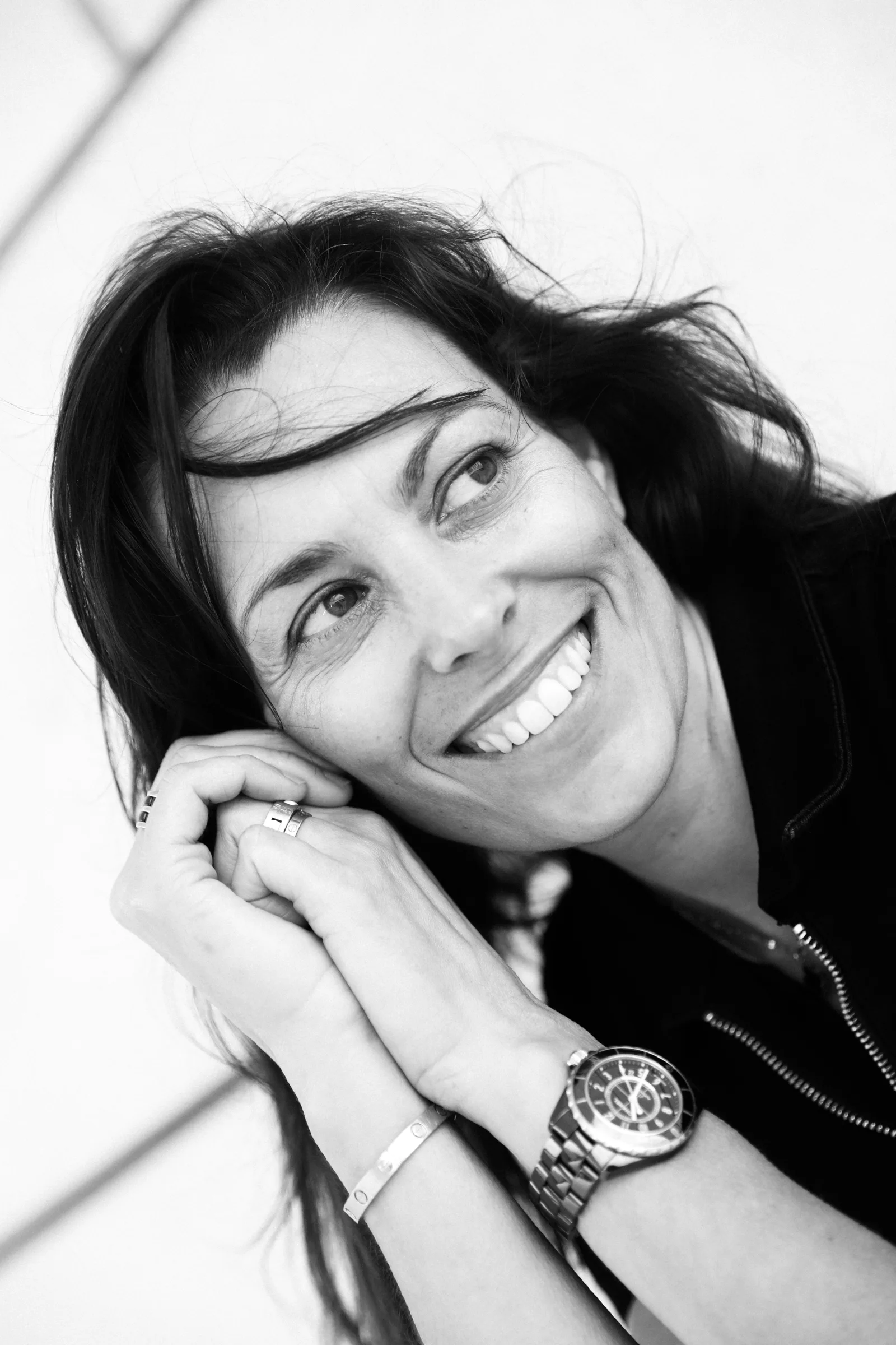 Portrait en noir et blanc de Cristina Gallice, souriante, les mains contre la joue